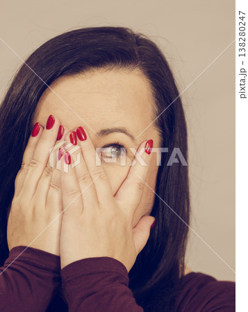 Woman peeking through her hands Woman peeking through her hands 138280247