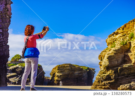 Woman with camera at Cathedral Beach in Spain. Woman with camera at Cathedral Beach in Spain. 138280573