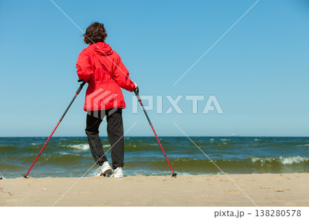 Nordic walking. Woman hiking on the beach. Nordic walking. Woman hiking on the beach. 138280578