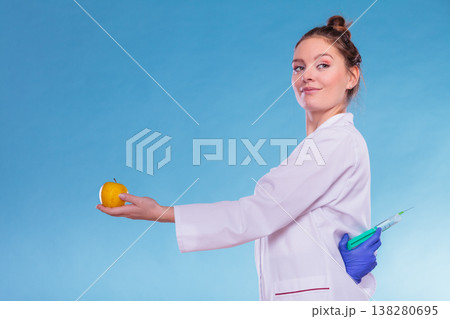Scientist doctor with apple and syringe. GM Food. 138280695