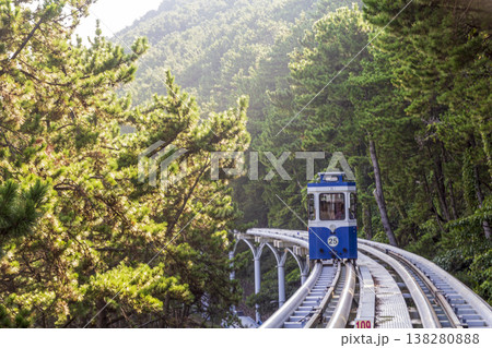 Colorful oceanfront capsule cars travel along an elevated coastal rail, offering scenic seaside views and a relaxed tourism experience over the water. High quality photo 138280888