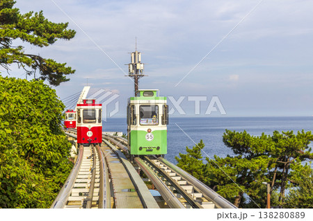 Colorful oceanfront capsule cars travel along an elevated coastal rail, offering scenic seaside views and a relaxed tourism experience over the water. High quality photo 138280889