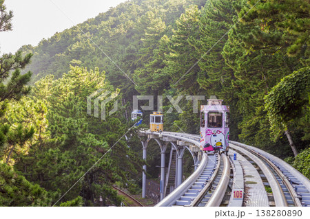 Colorful oceanfront capsule cars travel along an elevated coastal rail, offering scenic seaside views and a relaxed tourism experience over the water. High quality photo 138280890