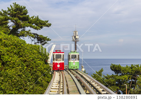 Colorful oceanfront capsule cars travel along an elevated coastal rail, offering scenic seaside views and a relaxed tourism experience over the water. High quality photo 138280891