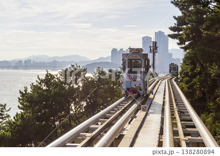 Colorful oceanfront capsule cars travel along an elevated coastal rail, offering scenic seaside views and a relaxed tourism experience over the water. High quality photo 138280894