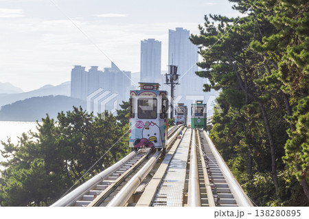 Colorful oceanfront capsule cars travel along an elevated coastal rail, offering scenic seaside views and a relaxed tourism experience over the water. High quality photo 138280895