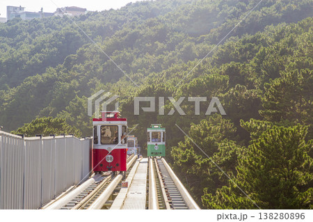 Colorful oceanfront capsule cars travel along an elevated coastal rail, offering scenic seaside views and a relaxed tourism experience over the water. High quality photo 138280896