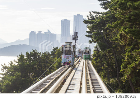 Colorful oceanfront capsule cars travel along an elevated coastal rail, offering scenic seaside views and a relaxed tourism experience over the water. High quality photo 138280918