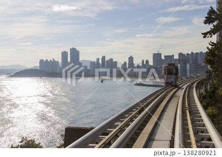 Colorful oceanfront capsule cars travel along an elevated coastal rail, offering scenic seaside views and a relaxed tourism experience over the water. High quality photo 138280921
