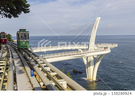 Colorful oceanfront capsule cars travel along an elevated coastal rail, offering scenic seaside views and a relaxed tourism experience over the water. High quality photo 138280924