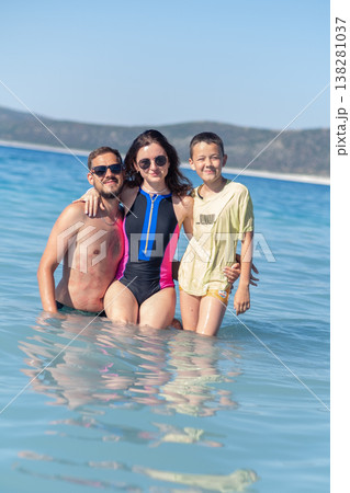 Family Enjoying a Sunny Day at the Beach While Playing in the Clear Water During Summer Vacation Family Enjoying a Sunny Day at the Beach While Playing in the Clear Water During Summer Vacation 138281037