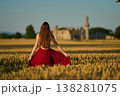 Woman rye field red dress. Happy woman in a long red dress in a beautiful cornfield. Old caste ruins in the background 138281075