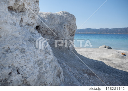 Beautiful Coastal Rock Formation Near Clear Blue Water at Sunny Beach in the Afternoon With Distant Mountains in the Background Beautiful Coastal Rock Formation Near Clear Blue Water at Sunny Beach in the Afternoon With Distant Mountains in the Background 138281142