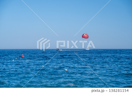 Parasailing Adventure Above Clear Blue Waters Near a Beach Under a Bright Sky With Boats Nearby Parasailing Adventure Above Clear Blue Waters Near a Beach Under a Bright Sky With Boats Nearby 138281154