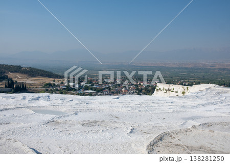 Natural Terraces of White Travertine in Pamukkale Overlook a Scenic Landscape With Lush Greenery and Distant Mountains Under a Clear Blue Sky 138281250