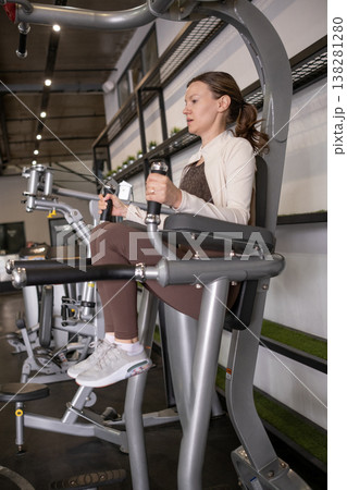 Woman Exercising on Gym Equipment in Modern Fitness Center While Focusing on Leg Strength Training Woman Exercising on Gym Equipment in Modern Fitness Center While Focusing on Leg Strength Training 138281280