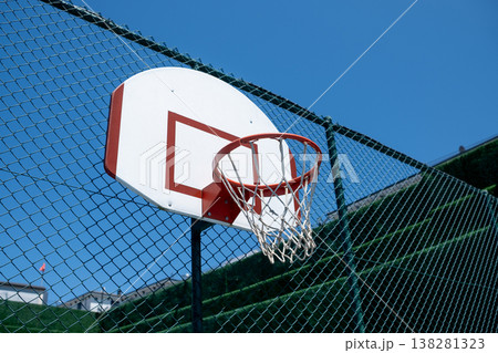 Basketball Hoop Attached to a Fence Under a Clear Blue Sky With a Few Clouds in the Background Basketball Hoop Attached to a Fence Under a Clear Blue Sky With a Few Clouds in the Background 138281323