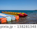Bright Yellow Banana Boat Resting at the Shoreline of a Clear Blue Ocean on a Sunny Day, Ready for Fun Water Sports 138281348