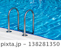 Swimming Pool With Stainless Steel Ladder and Shimmering Blue Water on a Sunny Day 138281350