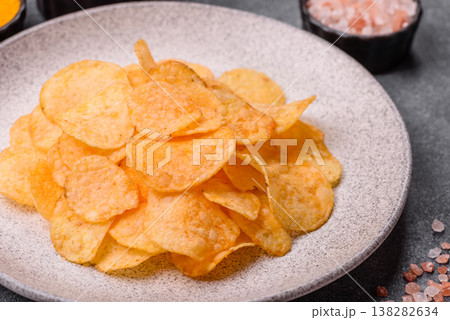 Crispy potato chips, golden slices seasoned with salt and spices. Potato chips Crispy potato chips, golden slices seasoned with salt and spices. Potato chips 138282634