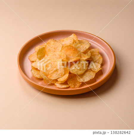 Crispy potato chips, golden slices seasoned with salt and spices. Potato chips Crispy potato chips, golden slices seasoned with salt and spices. Potato chips 138282642