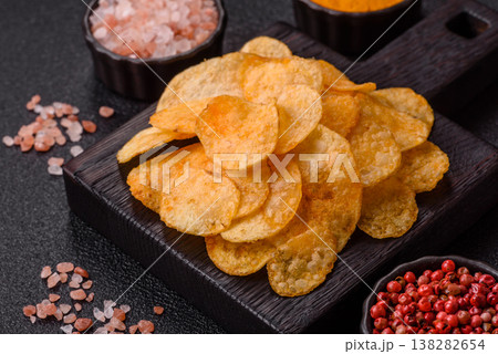 Crispy potato chips, golden slices seasoned with salt and spices. Potato chips Crispy potato chips, golden slices seasoned with salt and spices. Potato chips 138282654