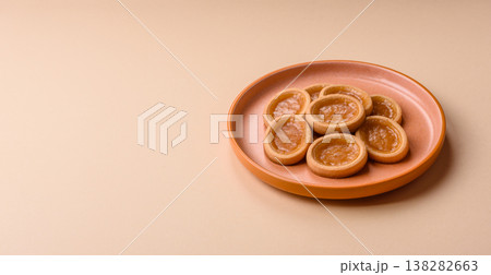 Round mini tartlets with citrus or peach jam and crumbly pastry. Mini citrus tarts 138282663