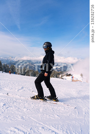 Male skier standing on snowy mountain slope with alpine landscape 138282716