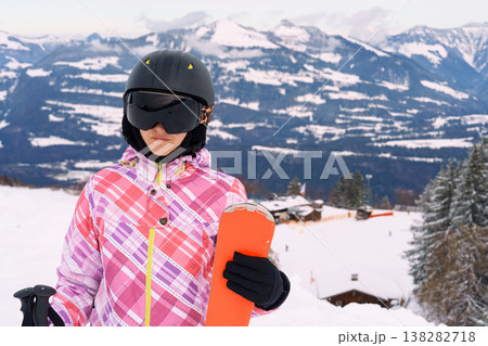 Female skier with skis on snowy mountain slope with alpine landscape 138282718