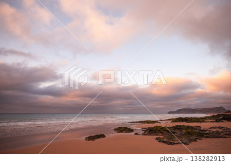Tranquil coastal scene of a sandy beach at sunset with pink clouds Tranquil coastal scene of a sandy beach at sunset with pink clouds 138282913