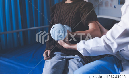Old woman training with physiotherapist using dumbbells at home. Therapist assisting senior woman with exercises in nursing home. Elderly patient using dumbbells with outstretched arms. 138283043