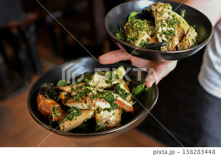 Chef serving gourmet seafood dishes with herbs and sauce presentation 138283448