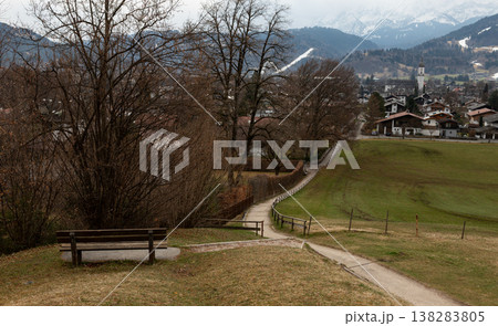 Bavarian alpine village landscape with bench, winding path and mountains Bavarian alpine village landscape with bench, winding path and mountains 138283805