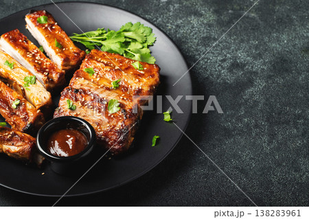 Hot grilled spare ribs from a summer BBQ served on a plate with sauce. Top view. Copy space 138283961