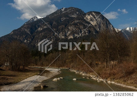 Clear alpine river beneath rugged mountain and blue sky 138285062