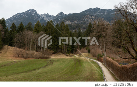 Narrow path through meadow toward forest and mountain ridge 138285068