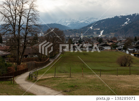 Path descending toward alpine town under dramatic sky Path descending toward alpine town under dramatic sky 138285071