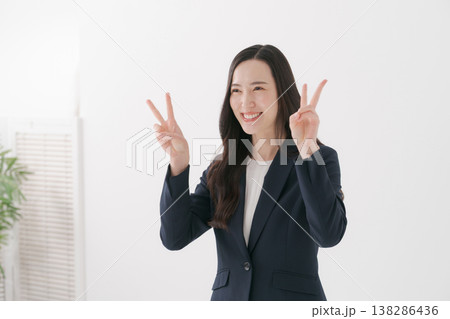 ピースするスーツの女性 138286436