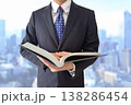 本を開くスーツ男性と都市背景 138286454
