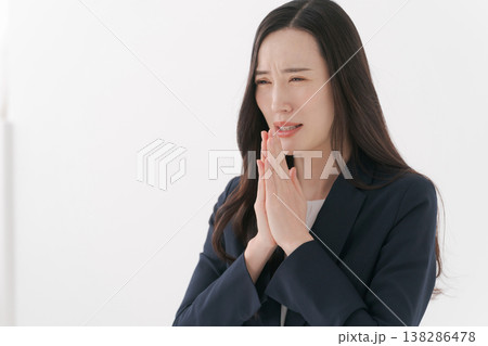 お願いのポーズをするスーツの女性 138286478