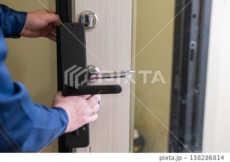 The technician installs a smart electronic lock on the front door. 138286814