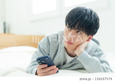 ベッドでスマホを見る男性 ベッドでスマホを見る男性 138287574