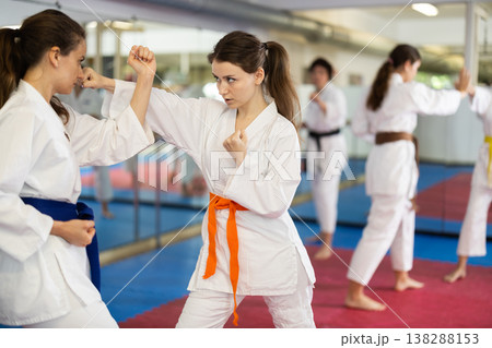 Womens practicing new karate moves in pairs in class with trainer Womens practicing new karate moves in pairs in class with trainer 138288153
