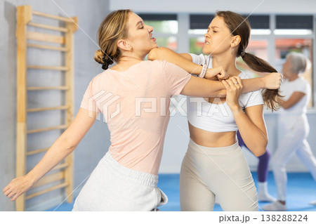 Woman practicing hand blocking with elbow strike to chin during sparring at self-defense training 138288224