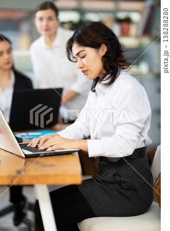 Young woman works on laptop with female colleagues Young woman works on laptop with female colleagues 138288280