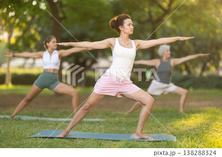 Woman performing asanas during group yoga session in park 138288324