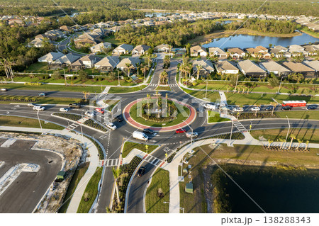 Aerial view of roundabout intersection on American road with moving traffic cars. Urban circular transportation crossroads Aerial view of roundabout intersection on American road with moving traffic cars. Urban circular transportation crossroads 138288343