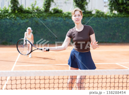 Young woman playing doubles tennis on court Young woman playing doubles tennis on court 138288454