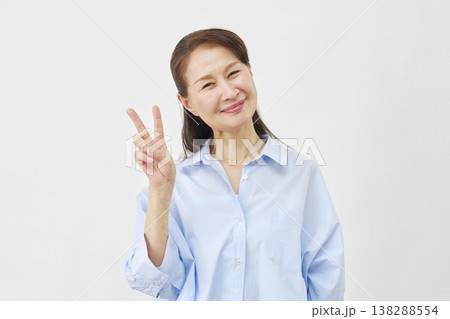 白背景でピースサインをする女性 138288554