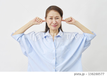 白背景で耳を塞ぐ高齢女性 138288577